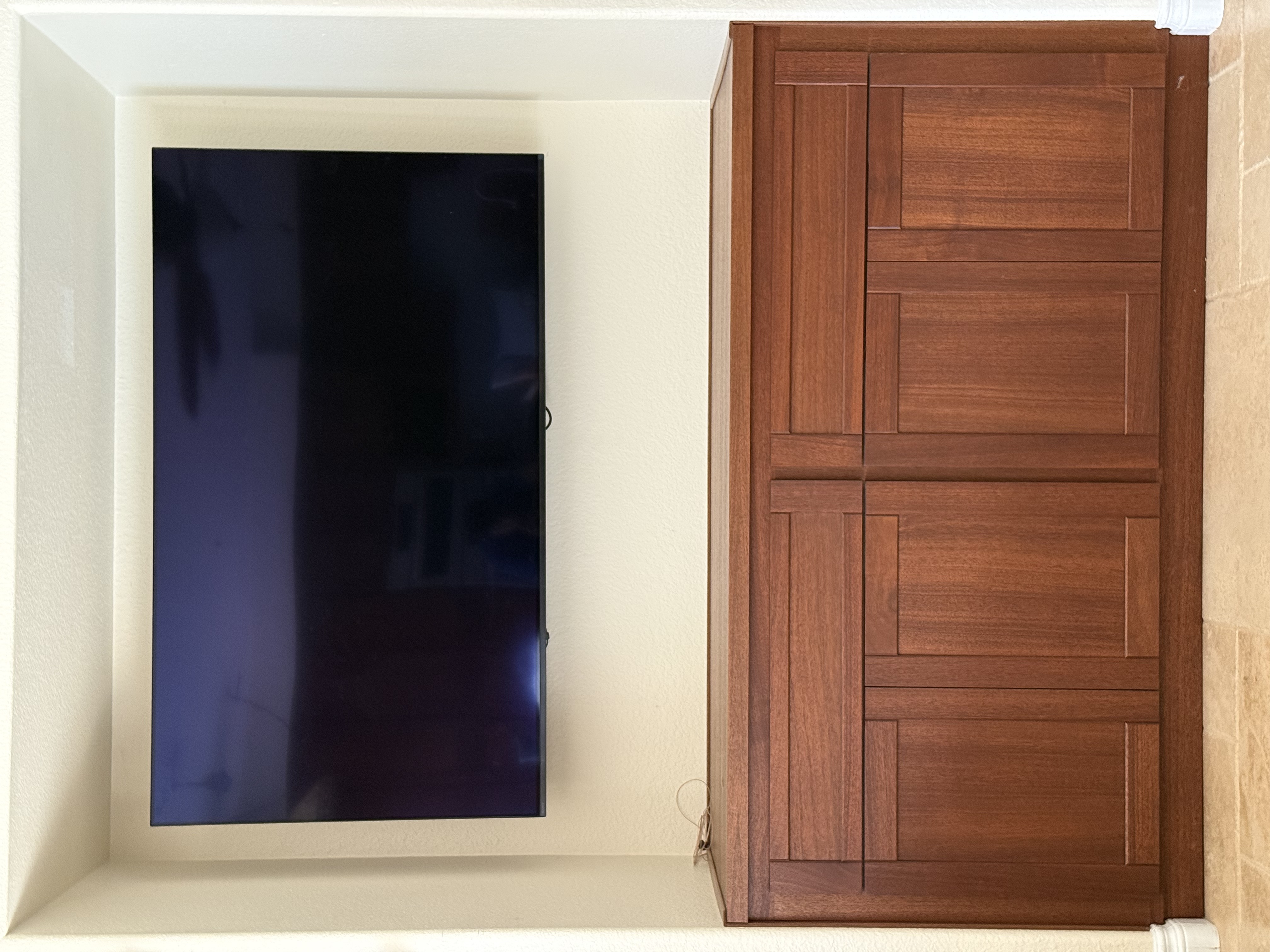 Built-in mahogany console fitted into a media wall alcove beside a mounted television