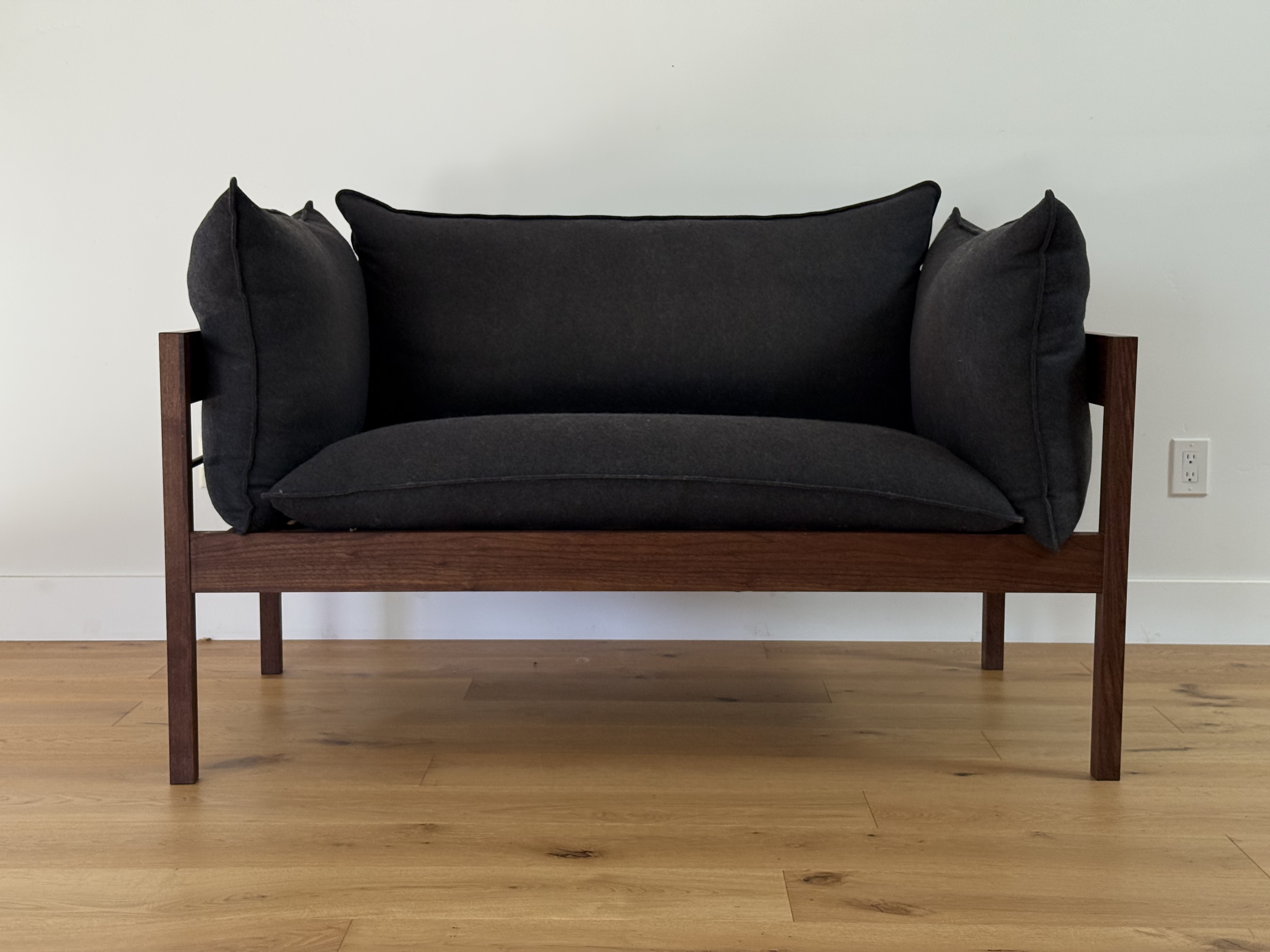 Walnut-framed loveseat with charcoal cushions, front view