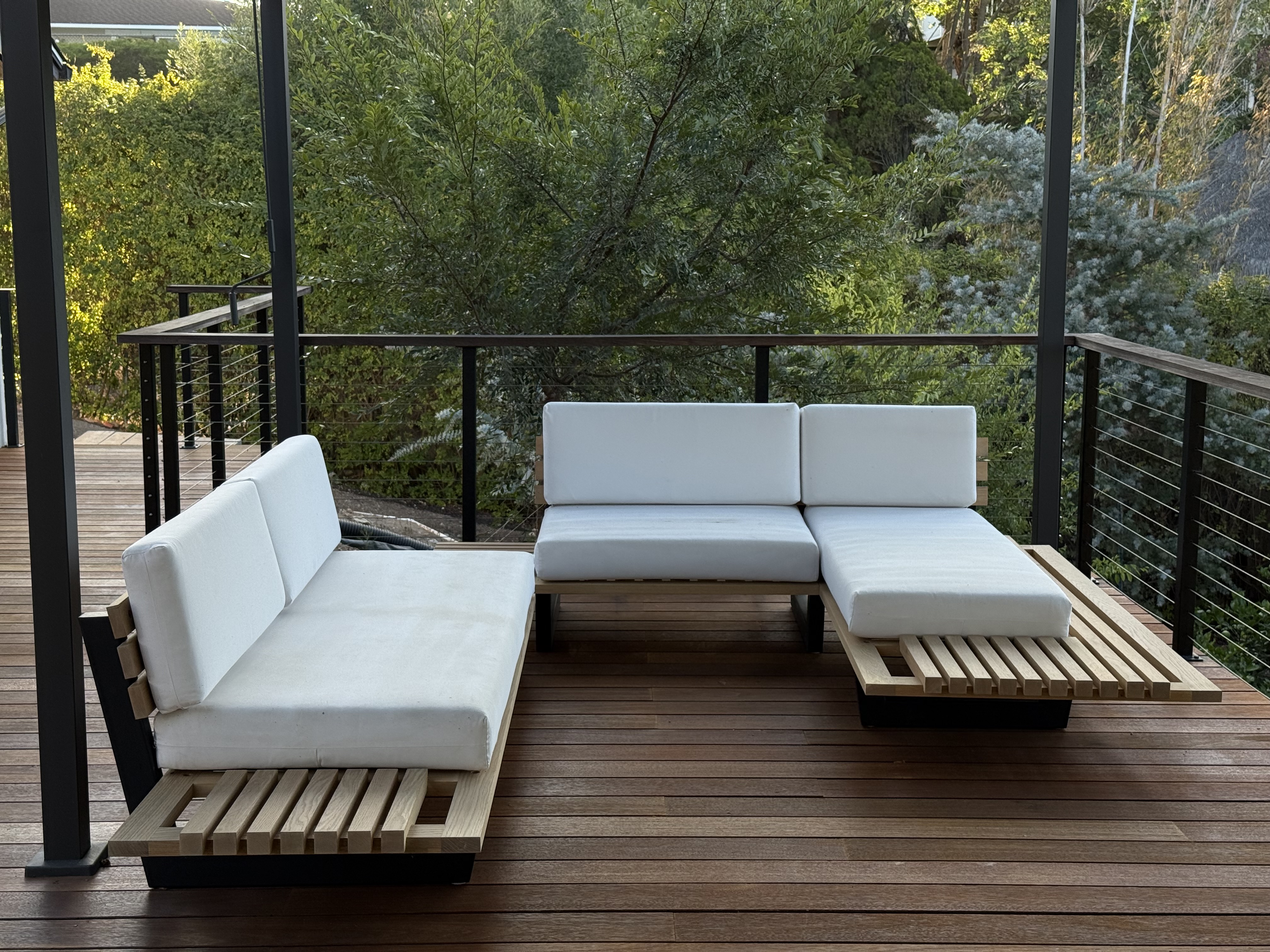 Outdoor sectional sofa, front view, solid hardwood frame with white cushions on a wood deck
