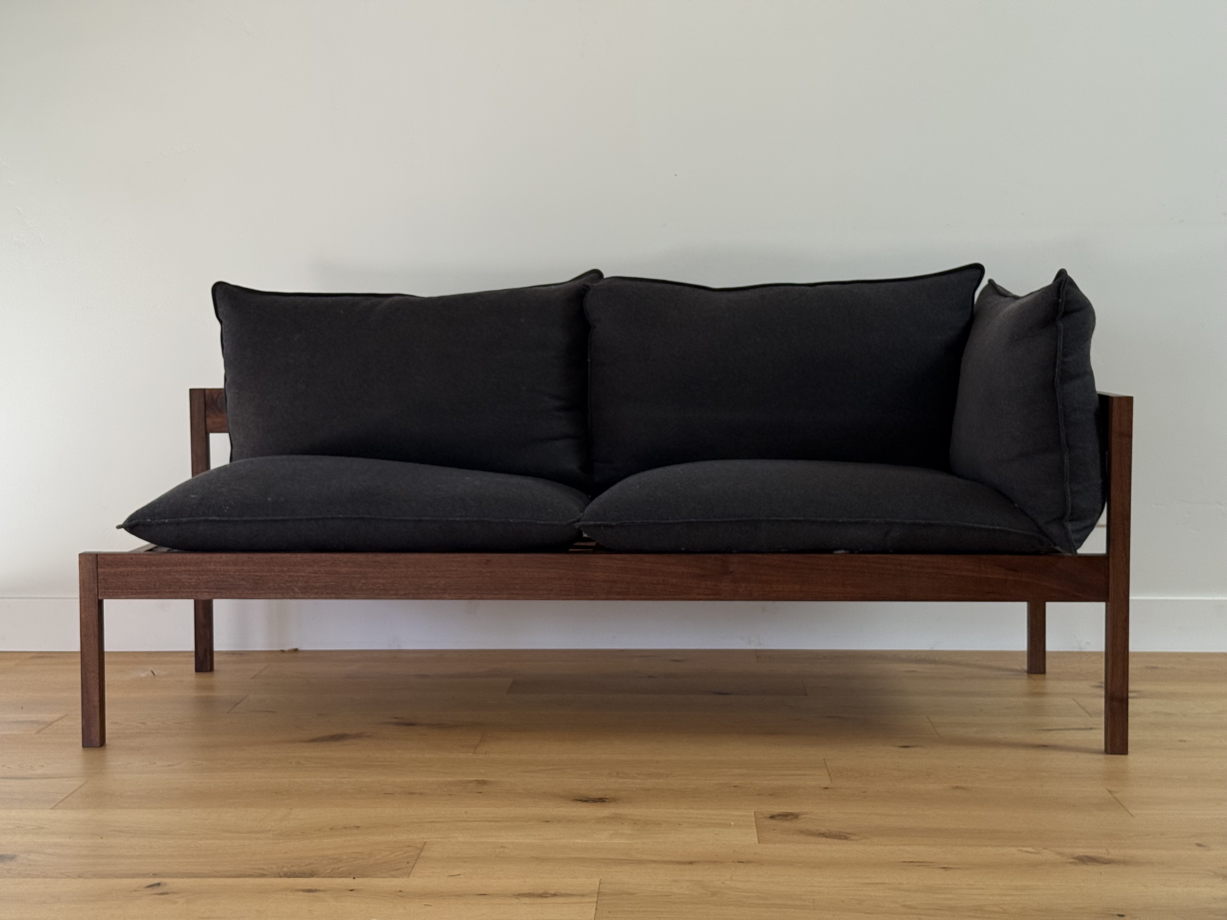 Walnut-framed sofa, front view with charcoal cushions